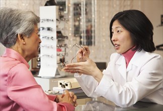 Korean optician showing eyeglasses to customer