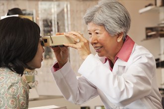 Chinese optician giving customer eye exam