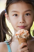 Mixed race girl eating ice cream cone