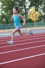 Mixed race girl running on track