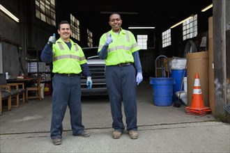 Sanitation workers giving thumbs up in garage