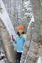 Mixed race girl standing on snowy tree