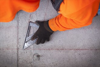 Construction worker marking cement