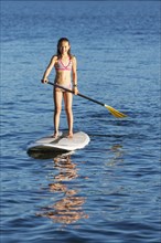 Mixed race girl paddle boarding