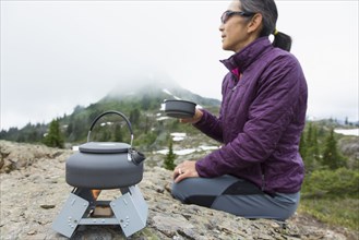 Japanese woman drinking coffee at campsite
