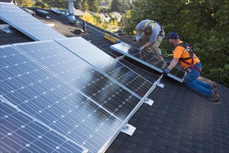 Caucasian men installing panels on roof