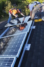 Caucasian men installing panels on roof
