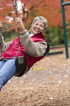 Mixed race woman on swing in park