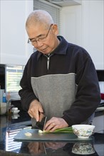 Chinese man chopping onions in kitchen