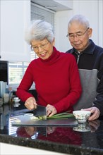 Chinese couple chopping onions in kitchen