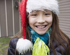 Mixed race girl in braces wearing Santa hat