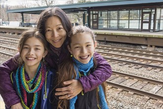 Mother and daughters smiling at train station