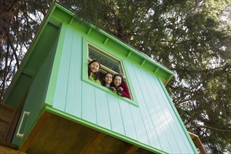 Girls leaning out tree house window