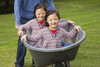 Twins with Down's Syndrome smiling in wheelbarrow