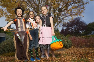 Children in Halloween costumes under autumn tree