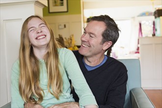 Caucasian father and daughter laughing in living room