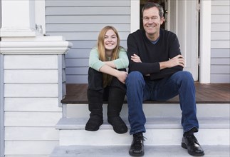 Caucasian father and daughter smiling on steps