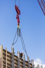 Crane attached to concrete wall form on construction site