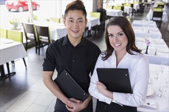 Waiter and waitress smiling together in restaurant