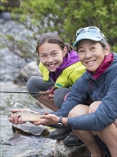 Mother and daughter fishing in river