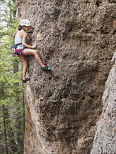 Mixed race girl climbing steep cliff