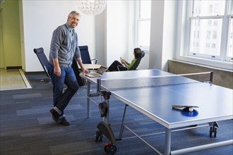 Businessman standing at table tennis table in office