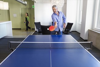 Businessman playing table tennis in office
