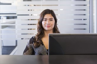 Mixed race businesswoman working at computer in office