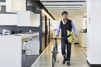 Caucasian businessman with bicycle in office