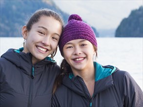 Mixed race sisters smiling at lake