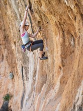 Mixed race girl climbing rock wall