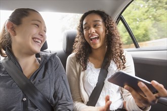 Teenage girls using cell phone in car back seat