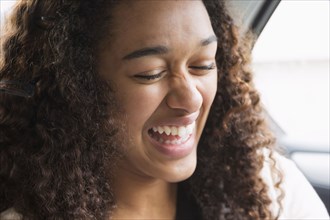 Mixed race teenage girl laughing in car back seat