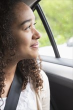 Mixed race teenage girl smiling in car back seat