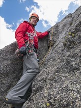 Caucasian climber using rope on rock
