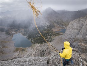 Caucasian climber throwing rope down mountainside