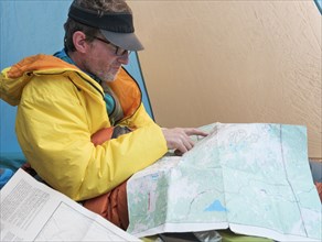 Caucasian man reading map in camping tent