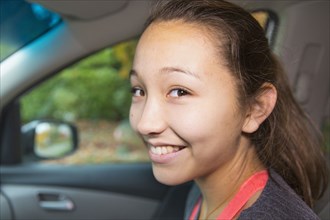 Mixed race girl smiling in car