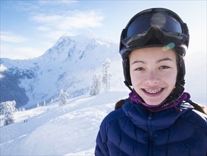 Mixed race girl smiling on snowy mountain