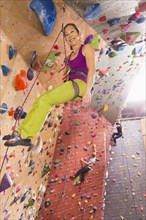 Smiling climber scaling rock wall