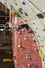 Mixed race teenage girl climbing rock wall