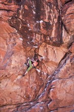 Mixed race teenage girl rock climbing on cliff
