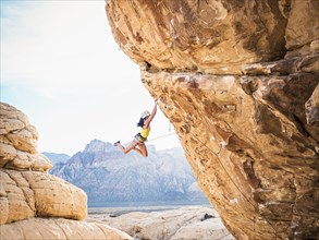 Mixed race girl rock climbing on cliff
