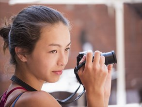 Mixed Race girl photographing outdoors with digital camera