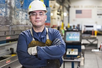 Serious Hispanic worker posing in factory