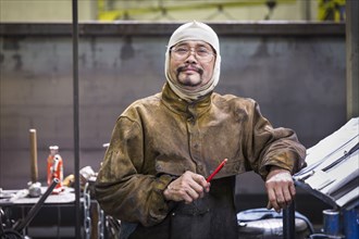 Smiling Asian worker wearing hood posing in factory