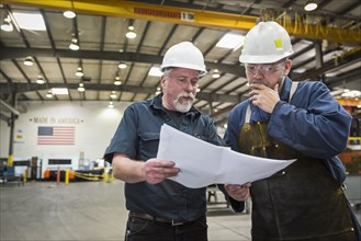 Workers examining paperwork in factory