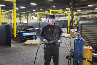 Caucasian welder posing with blowtorch in factory