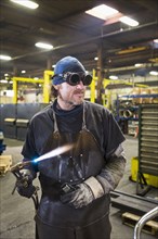 Caucasian welder holding  blowtorch in factory