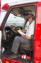 Caucasian semi-truck driver reading paperwork